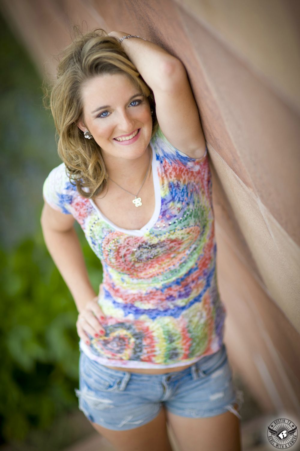 Smiling high school senior girl in very colorful shirt in Austin at Mueller Lake Park taken by Austin senior portrait photographer.